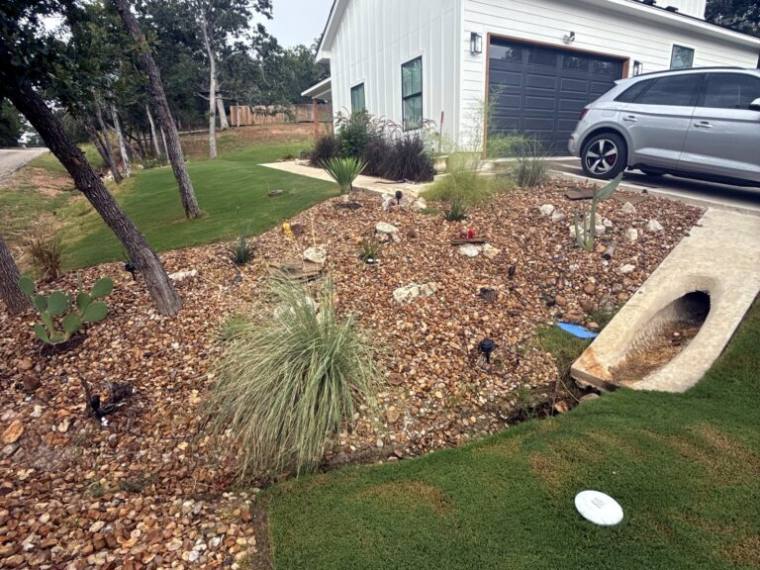 Native grasses and stone mulch bed beside a modern home driveway in Bastrop